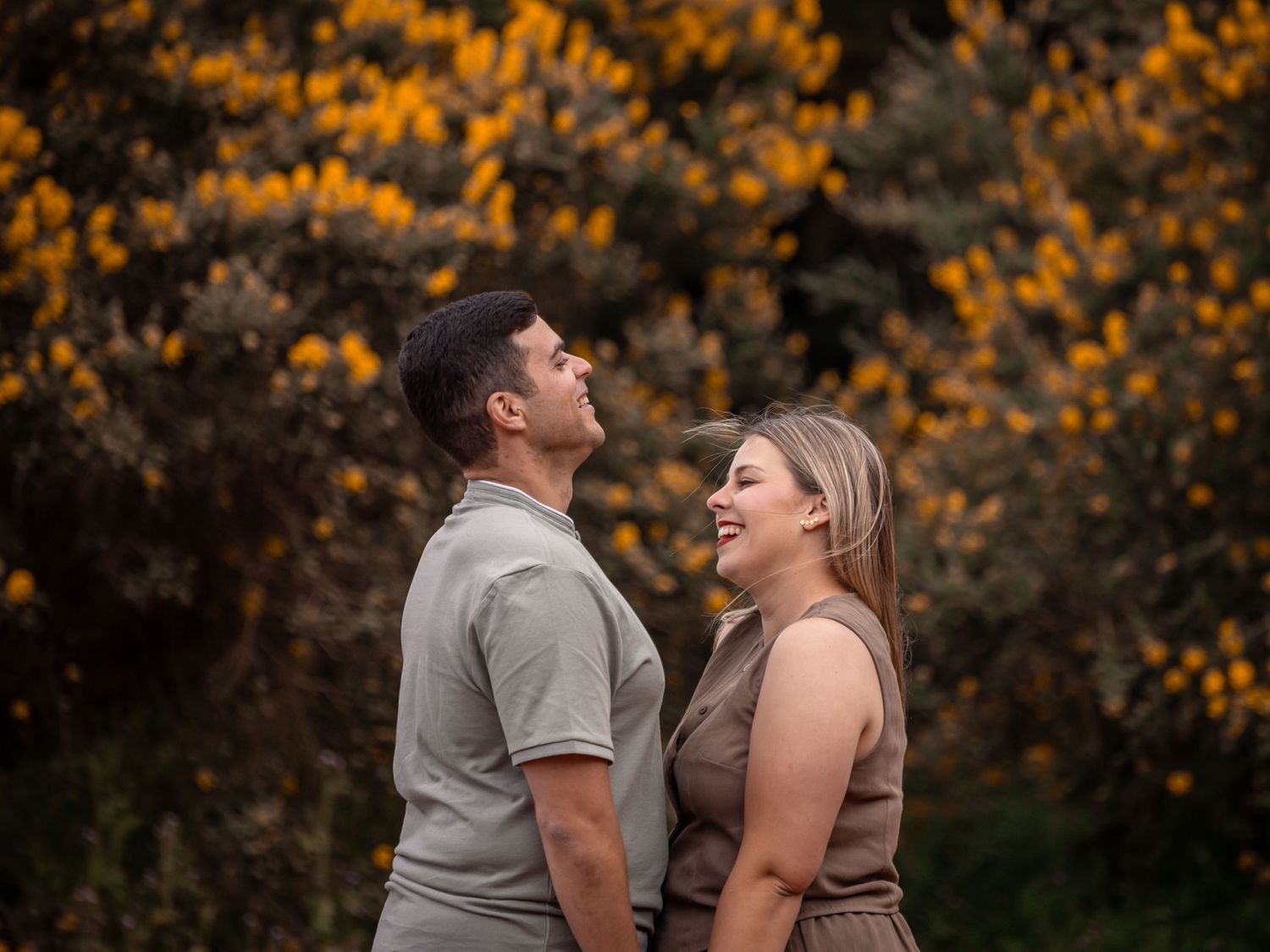 Couple sharing intimate moments among yellow wildflowers at golden hour.