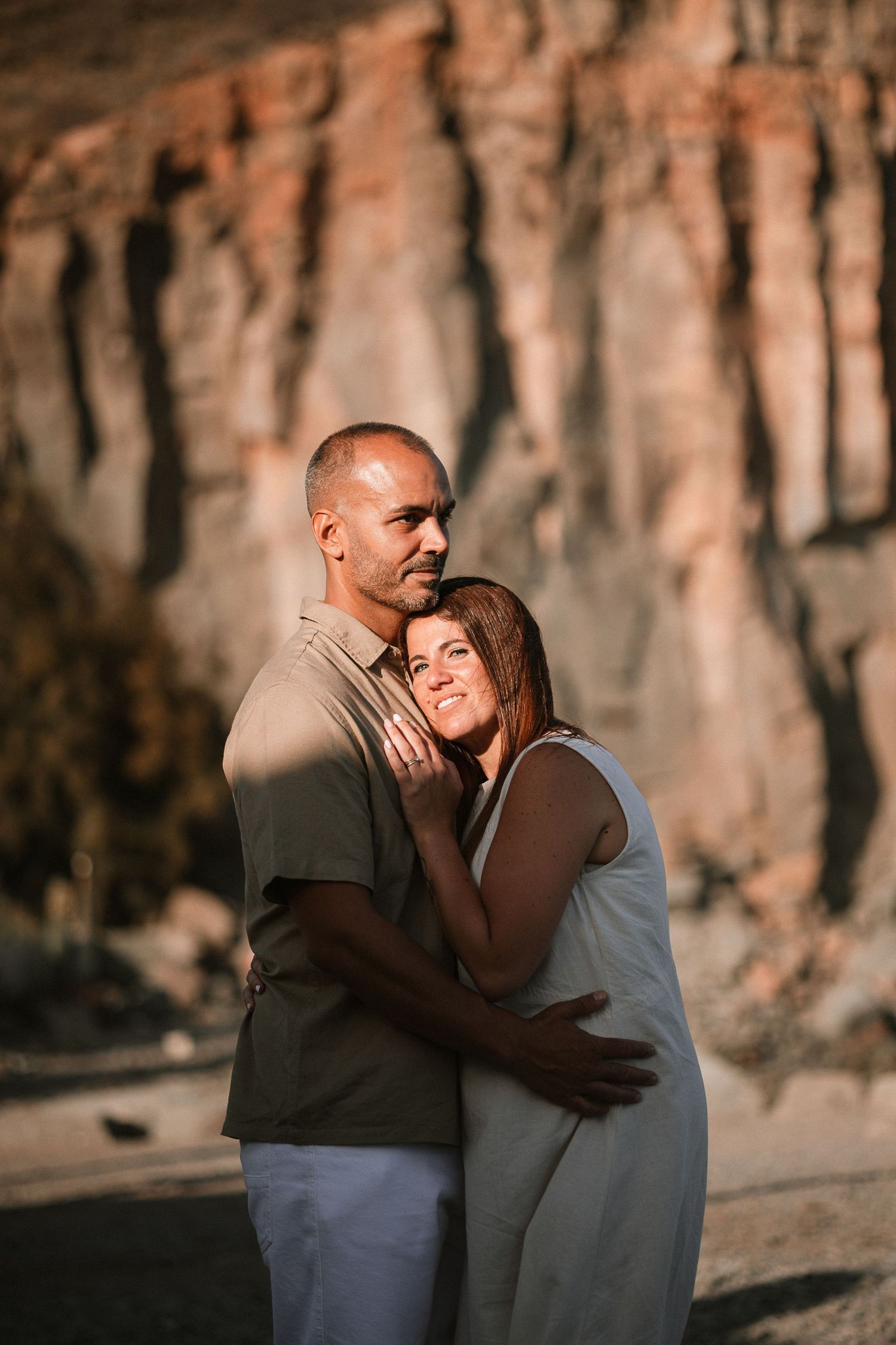 Intimate couple portraits against dramatic rocky cliffs during golden hour.