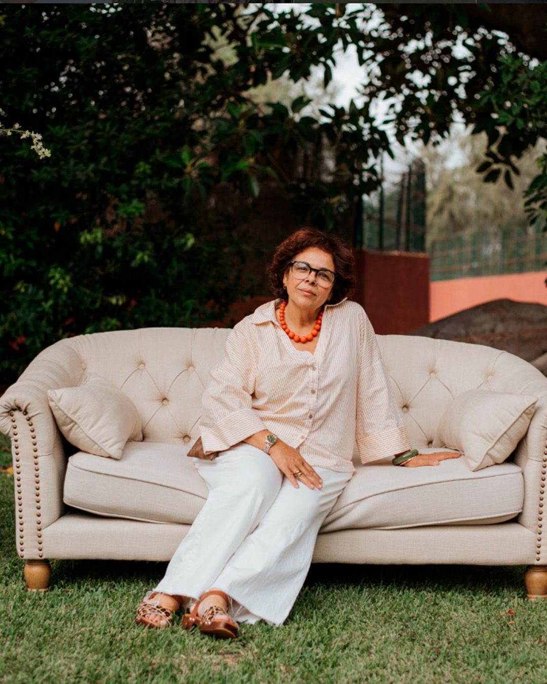 A person in white loungewear reclines on a beige couch outdoors in a series of relaxed poses.