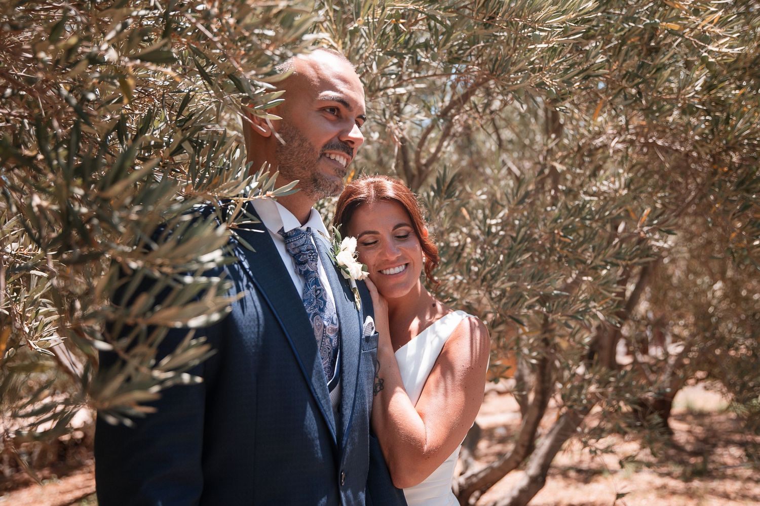 Couple shares an intimate moment under natural tree canopy during outdoor photoshoot.