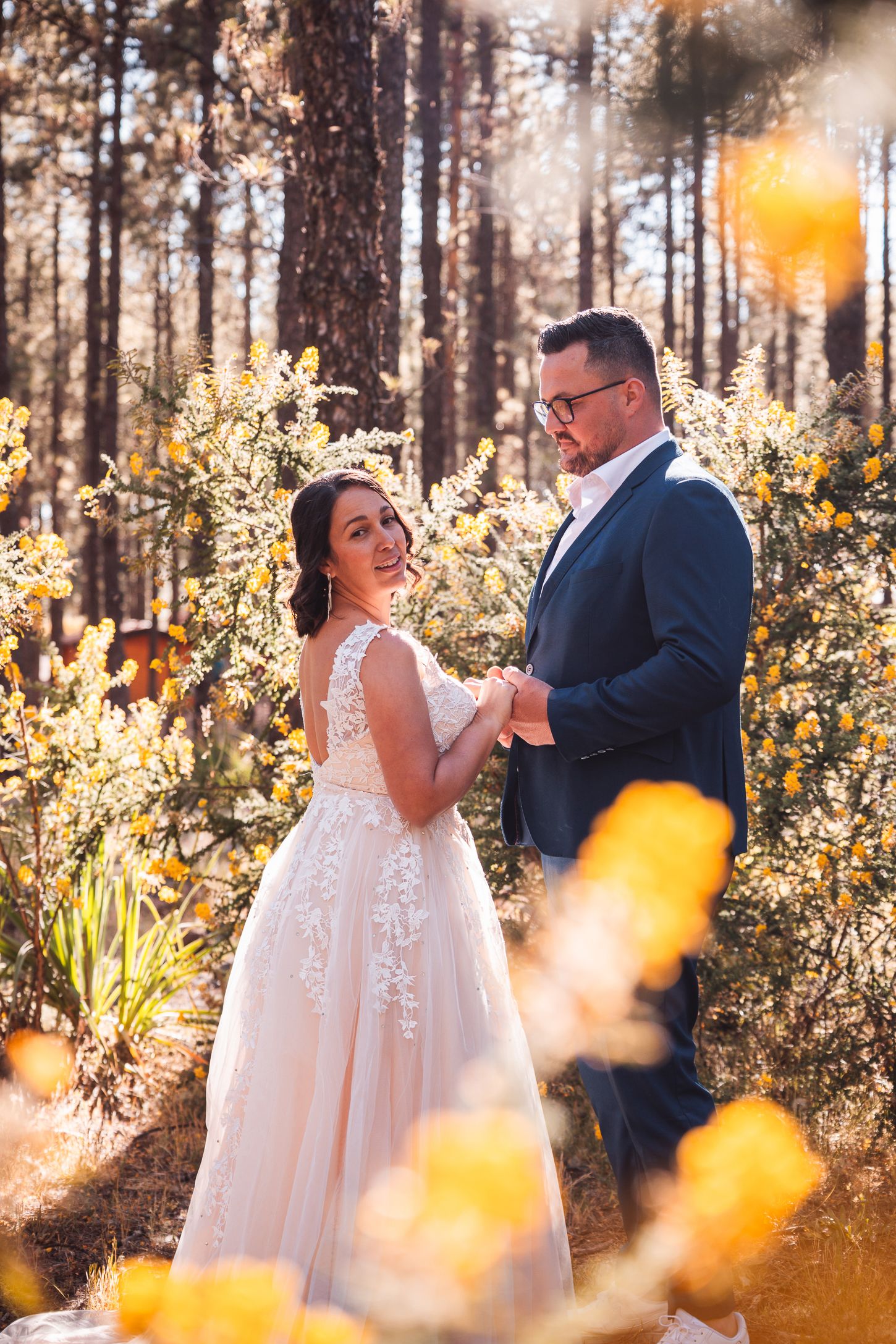 Romantic forest wedding photography with golden sunlight filtering through pine trees.
