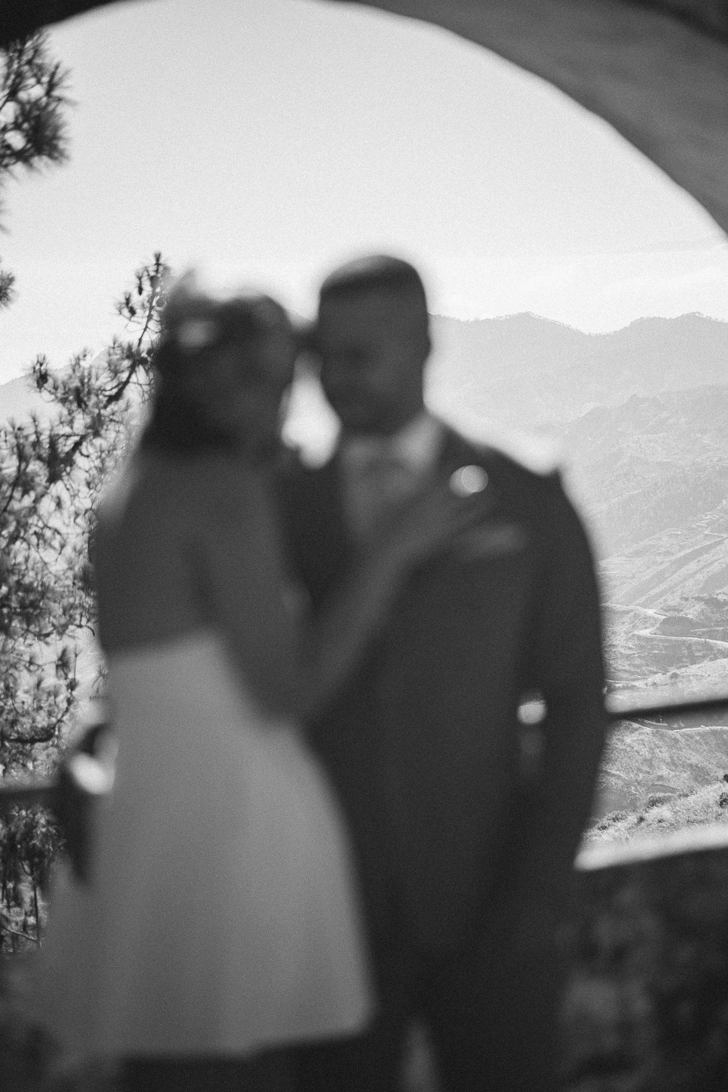 Silhouettes of a couple against a mountain landscape at dusk.