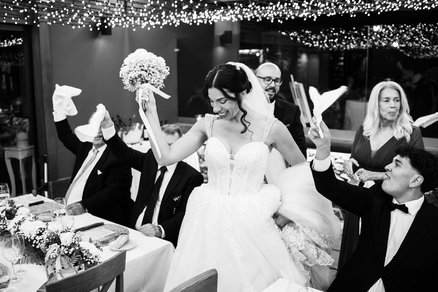 Wedding reception guests dancing and celebrating under sparkling lights.