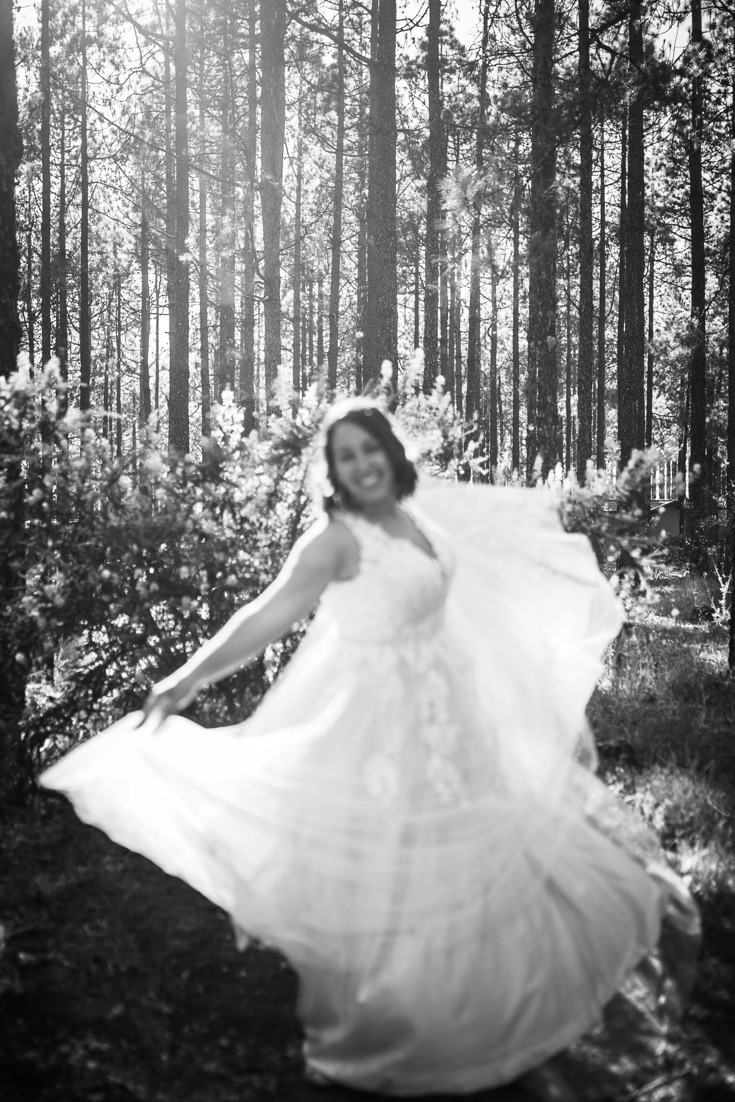 Flowing white wedding dress captured in motion against sunlit forest backdrop.