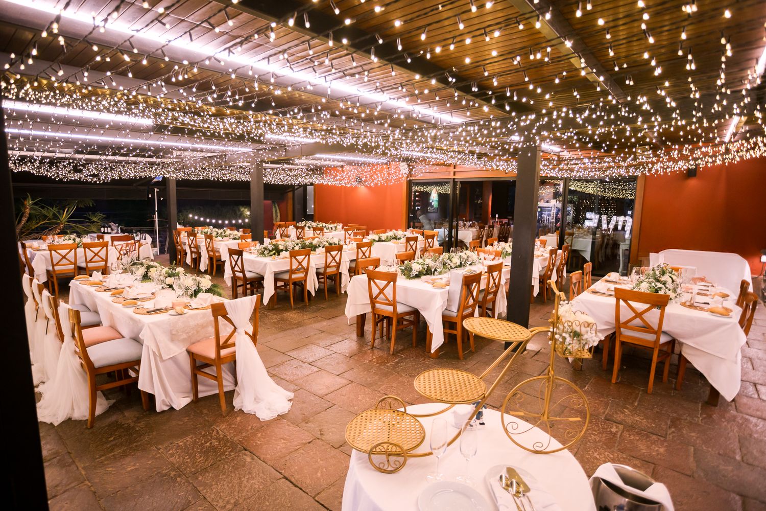An elegant wedding reception venue decorated with twinkling string lights and white table settings.