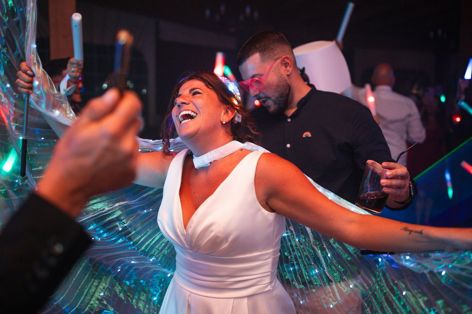 A group of people dancing and celebrating at a nightclub with colorful lights in the background.