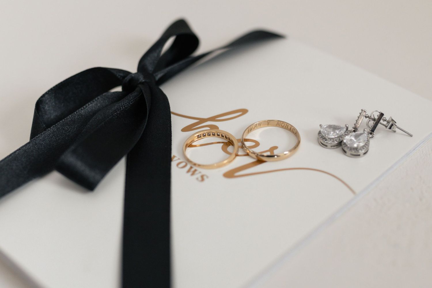 A collection of delicate gold and silver jewelry pieces arranged with black ribbon accents on a light background.