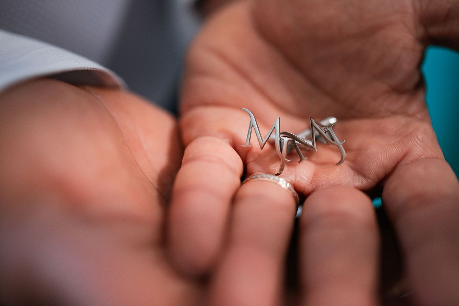 Close-up of hands holding wedding rings against blurred background.