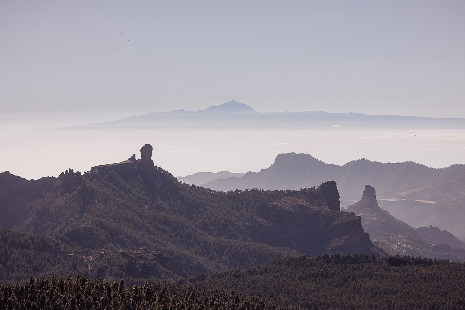Panoramic view of rugged mountain peaks and rock formations against a misty horizon at sunset.