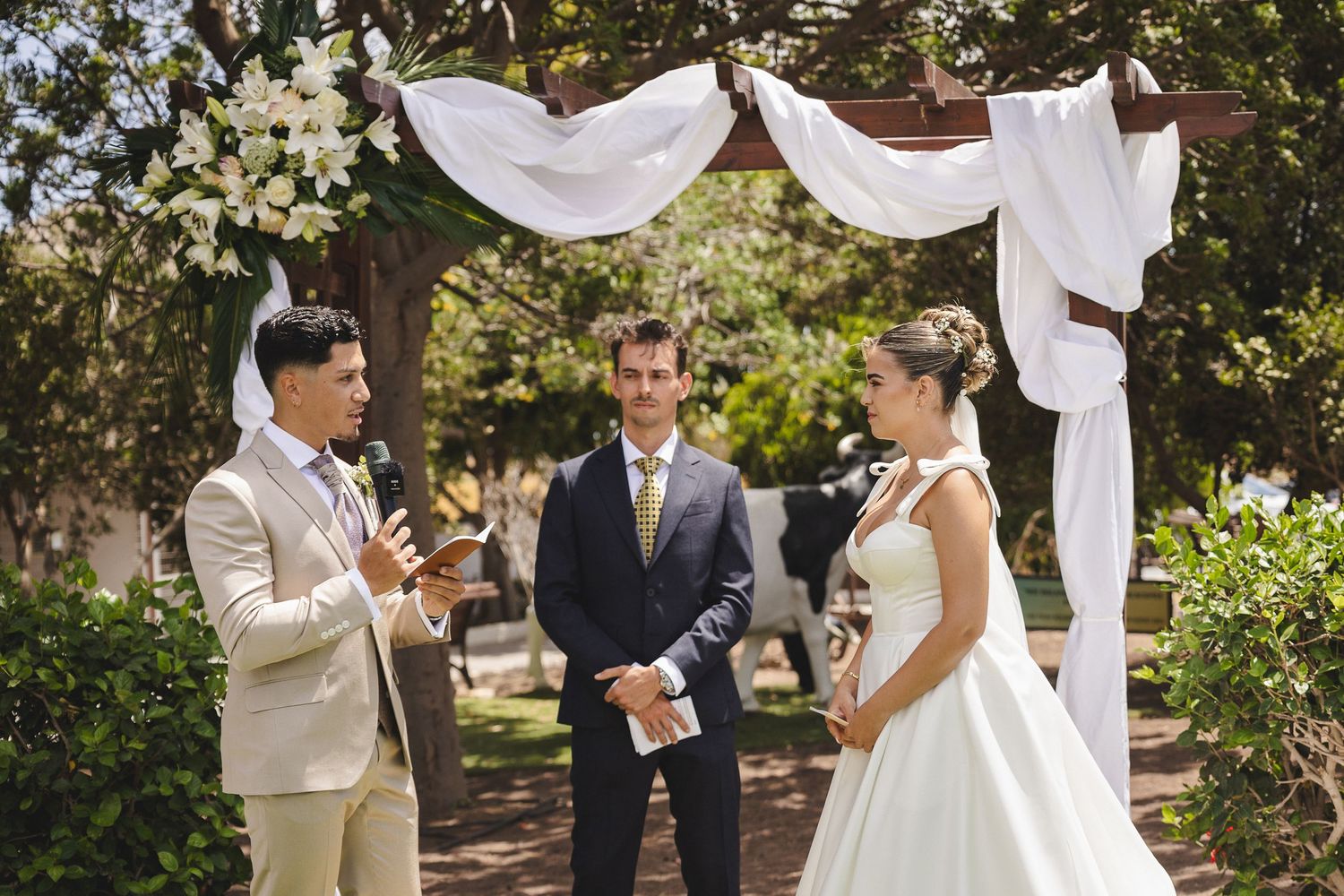 Elegant outdoor wedding ceremony setup with white drapes and floral arrangements.