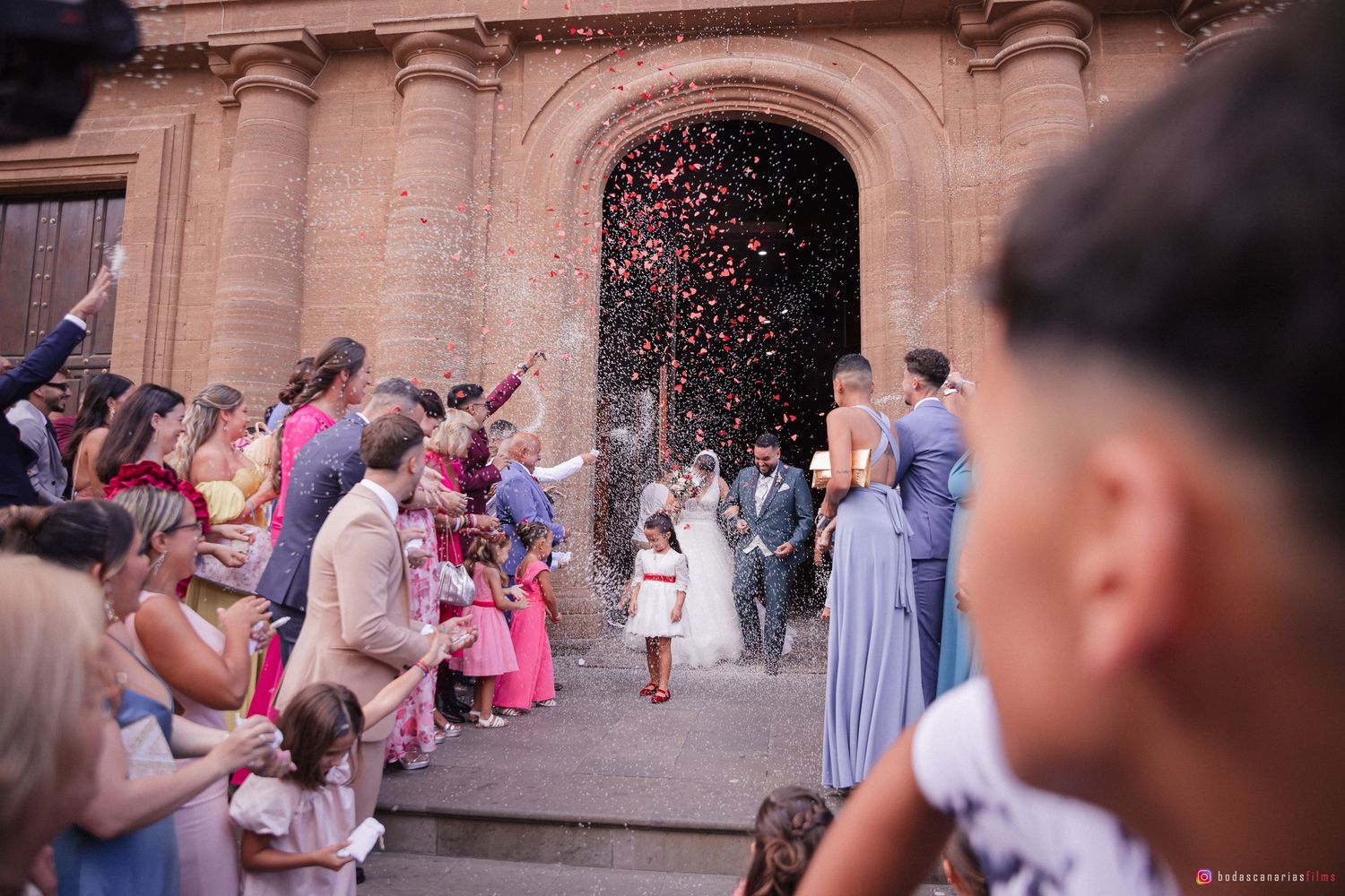 Large group of wedding guests gathered outside an ornate church entrance.