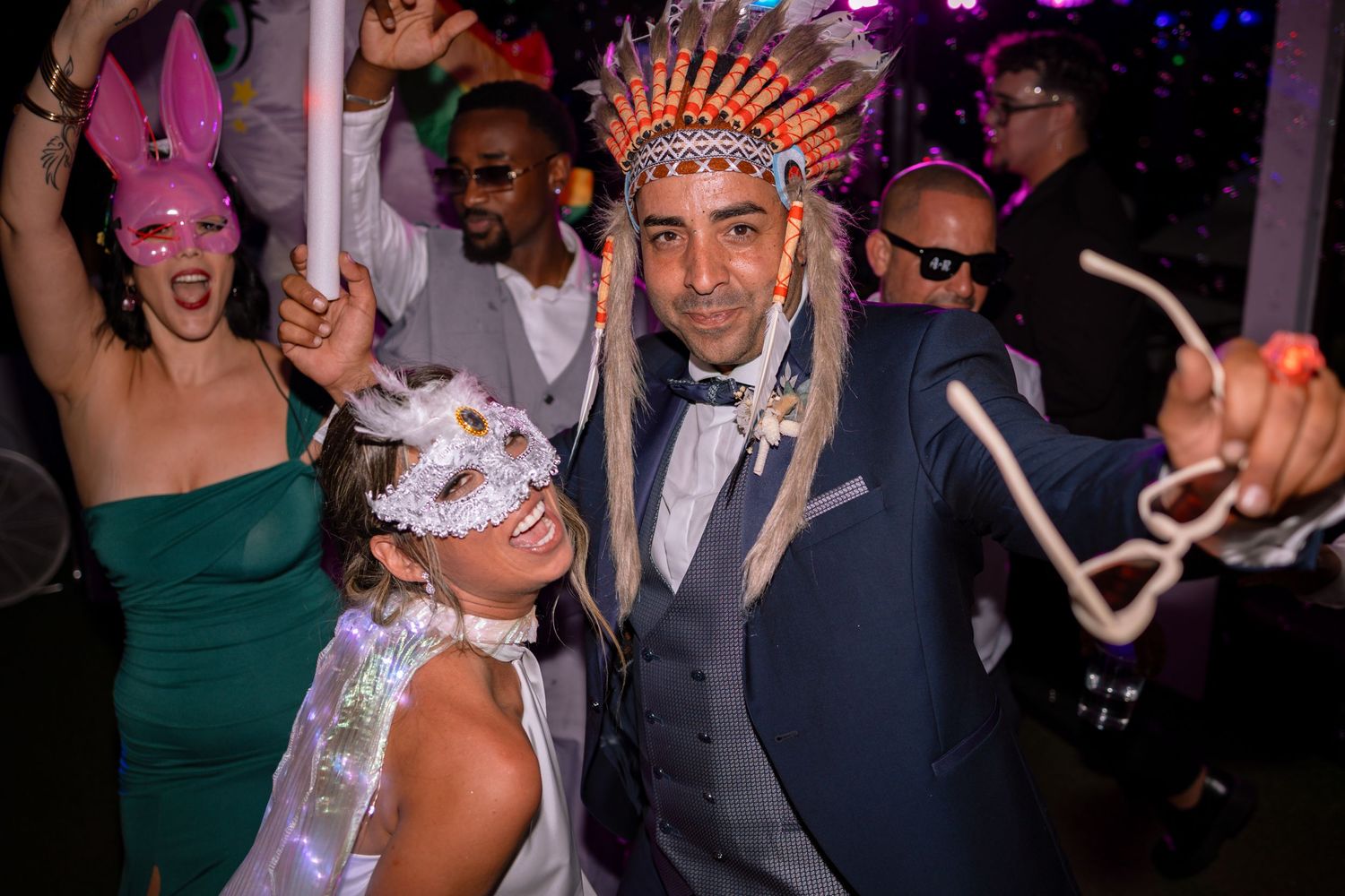 Energetic dance floor moments captured during a wedding reception with colorful lighting.