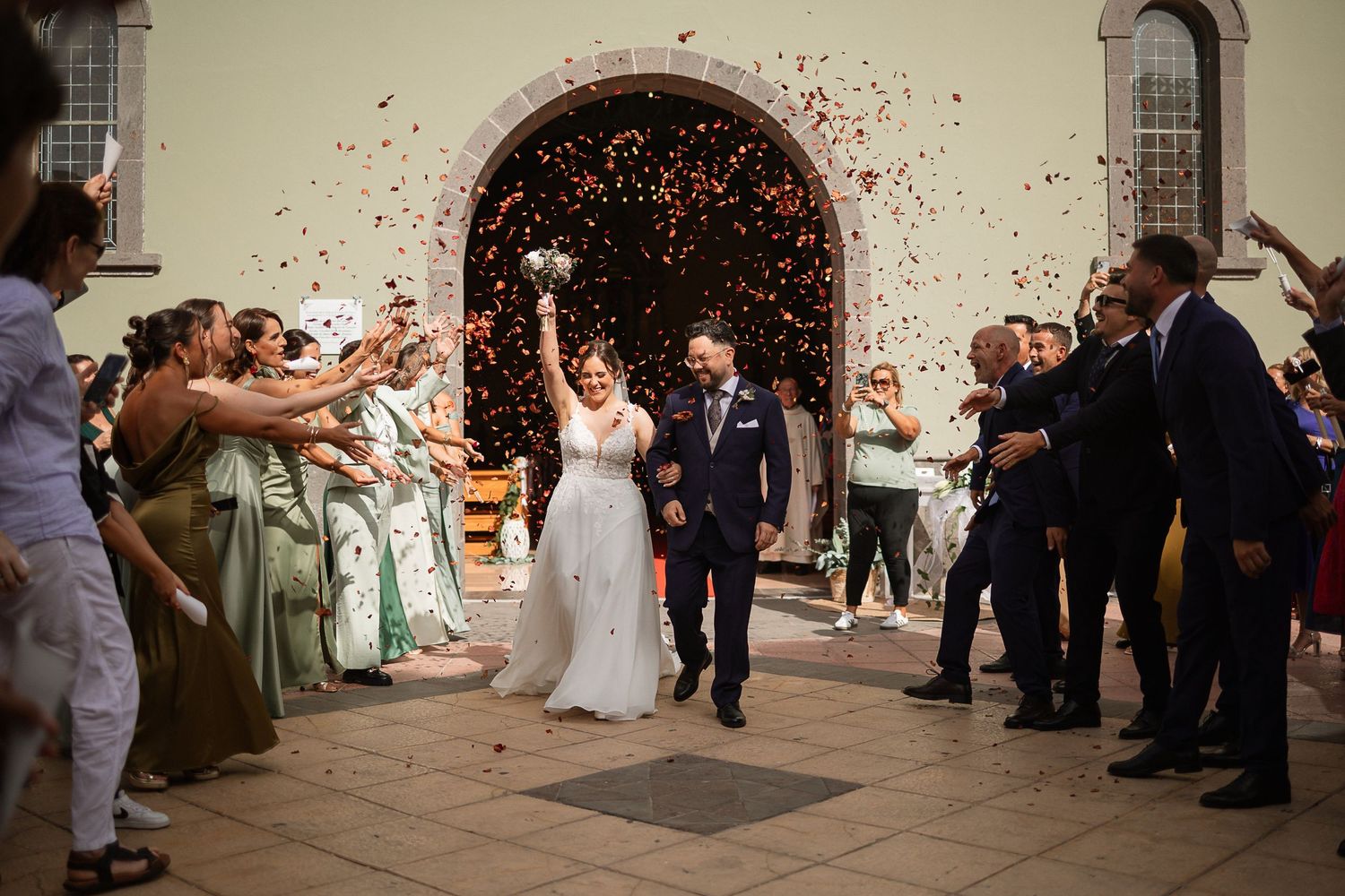 Wedding guests tossing confetti during celebration in an indoor venue.