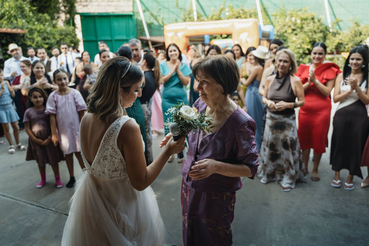 Two people share an emotional moment at an outdoor wedding ceremony surrounded by guests.