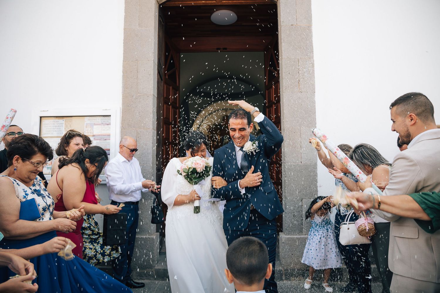 Wedding guests celebrating with confetti outside historic stone building.