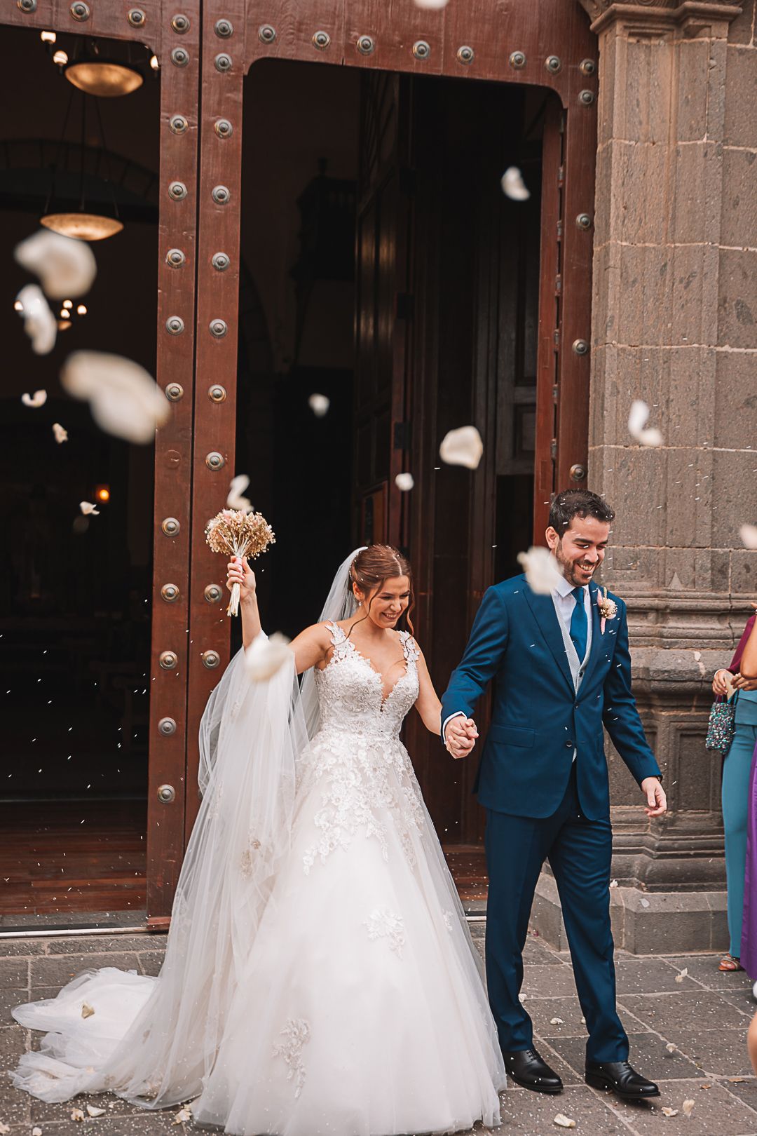 Newlyweds celebrate outside historic church doors as rose petals are tossed in celebration.