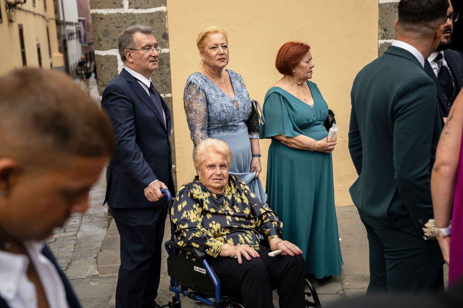 Wedding guests mingling outdoors in formal attire during a daytime reception.