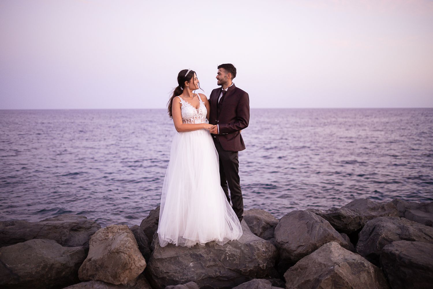Romantic sunset wedding photos captured on a rocky beach with ocean views.