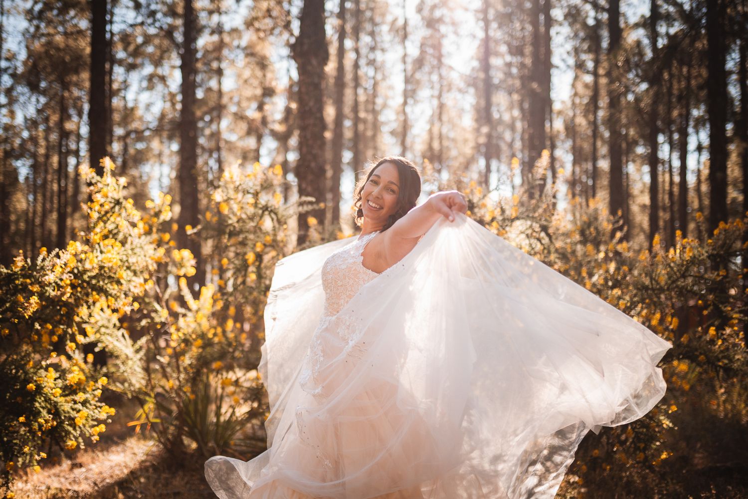 A romantic wedding photo series captured in a sunlit forest with golden light filtering through the trees.