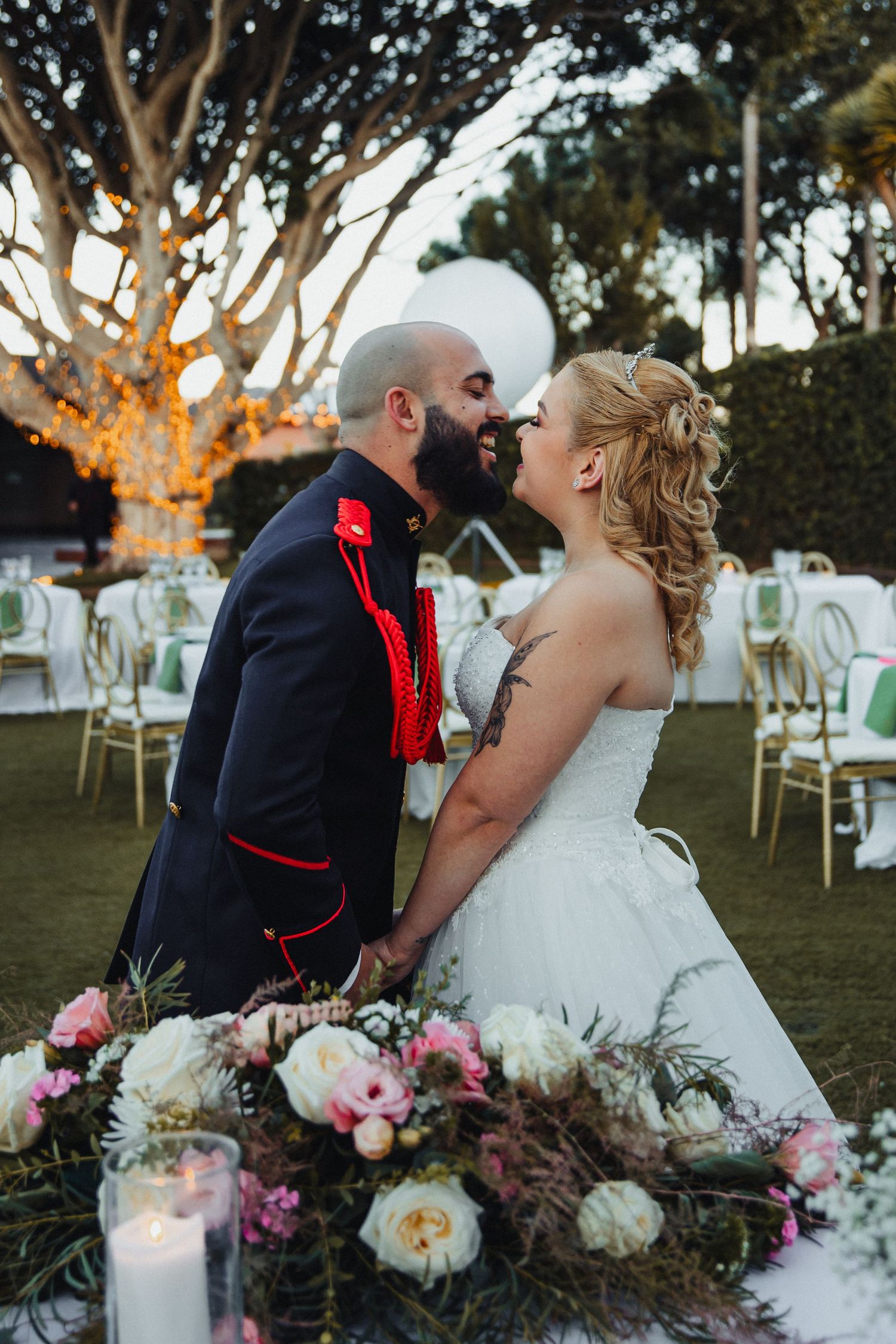 Newlyweds share romantic moments at their outdoor wedding reception with floral decorations.
