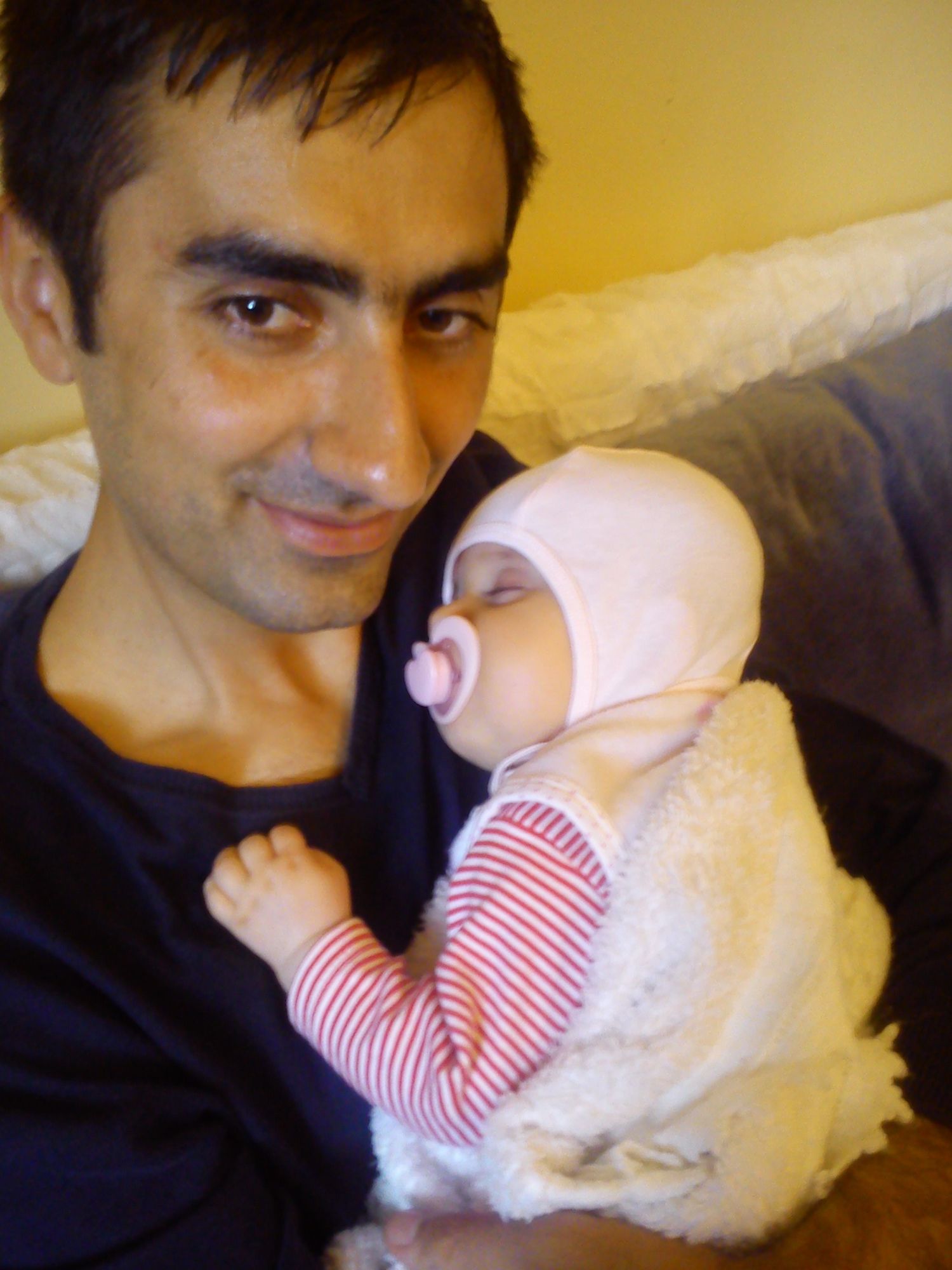 A series of photos showing a baby in a white and red striped outfit being held.