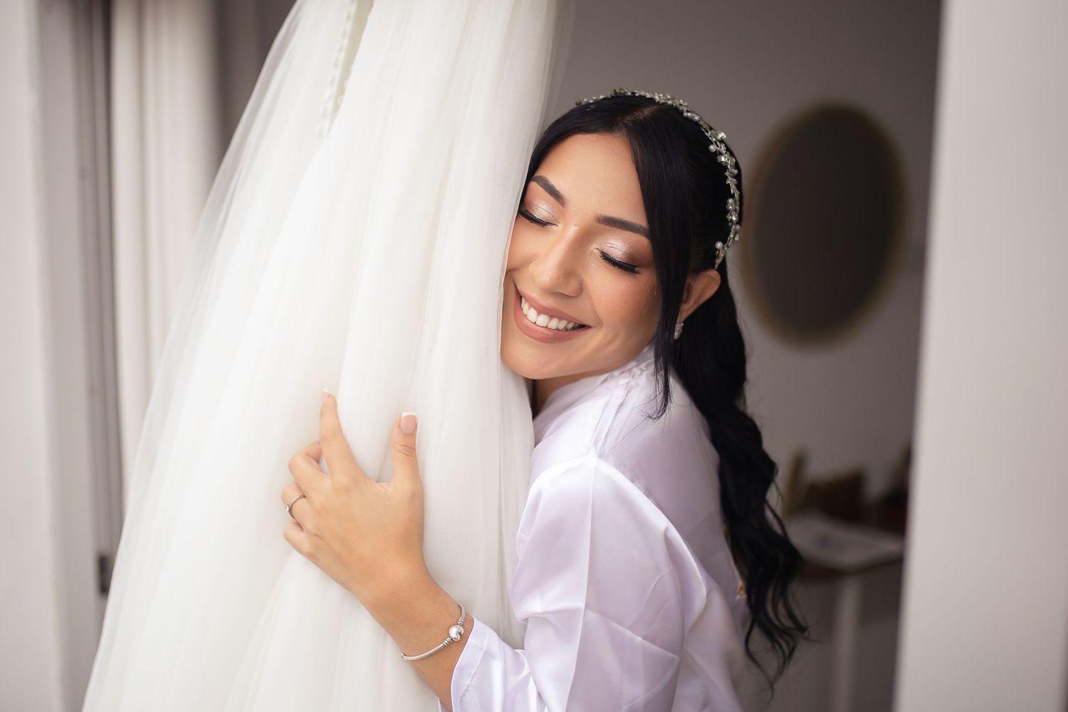 Flowing white wedding dress being held up against a light background.