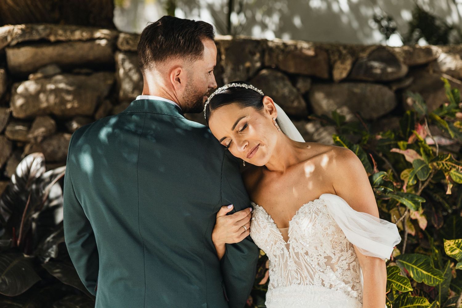 A romantic moment captured between a couple in formal wedding attire among garden foliage.