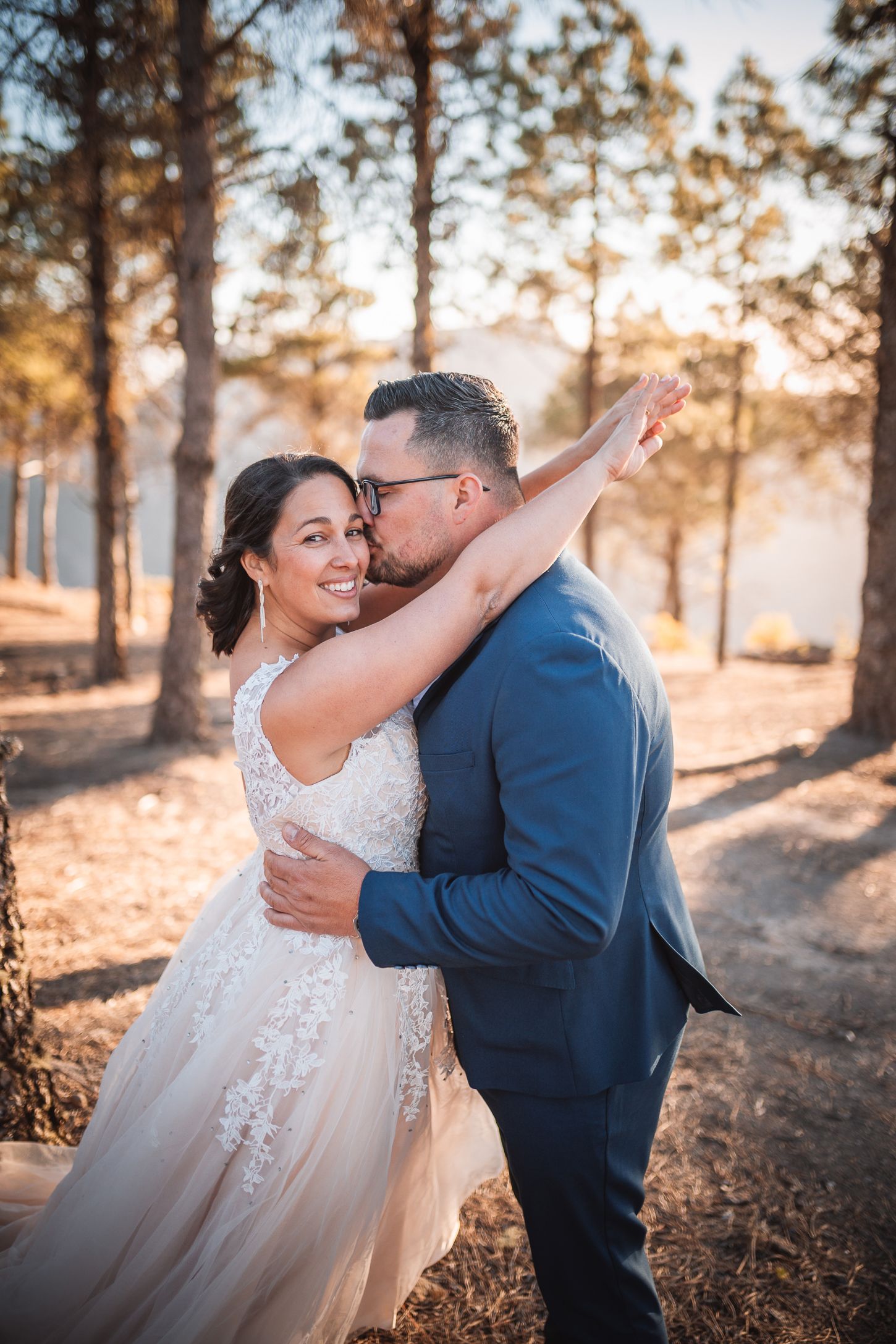 Romantic wedding photos capturing intimate moments between newlyweds in a golden-lit forest setting.