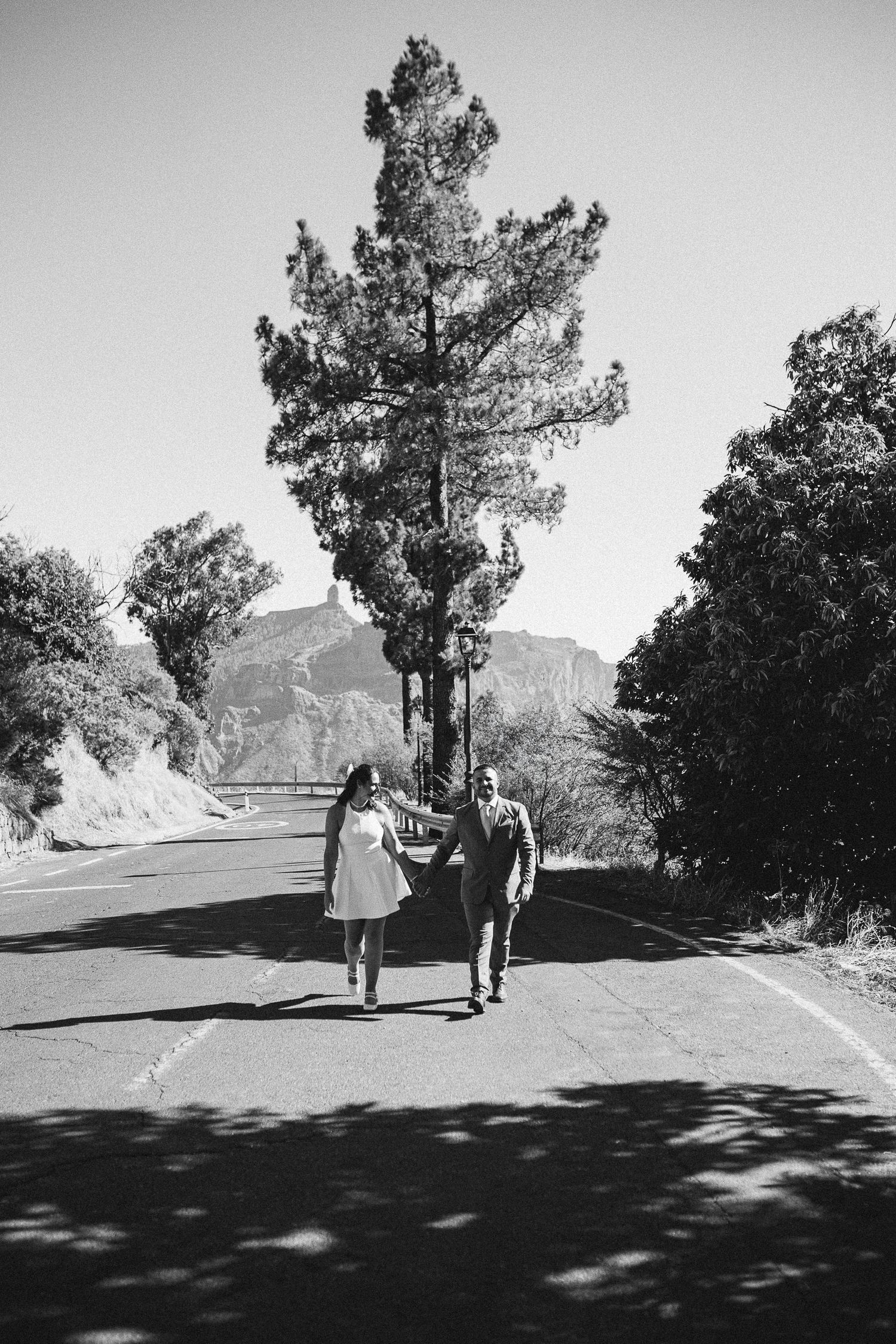 A black and white photo of a couple walking on a mountain path.