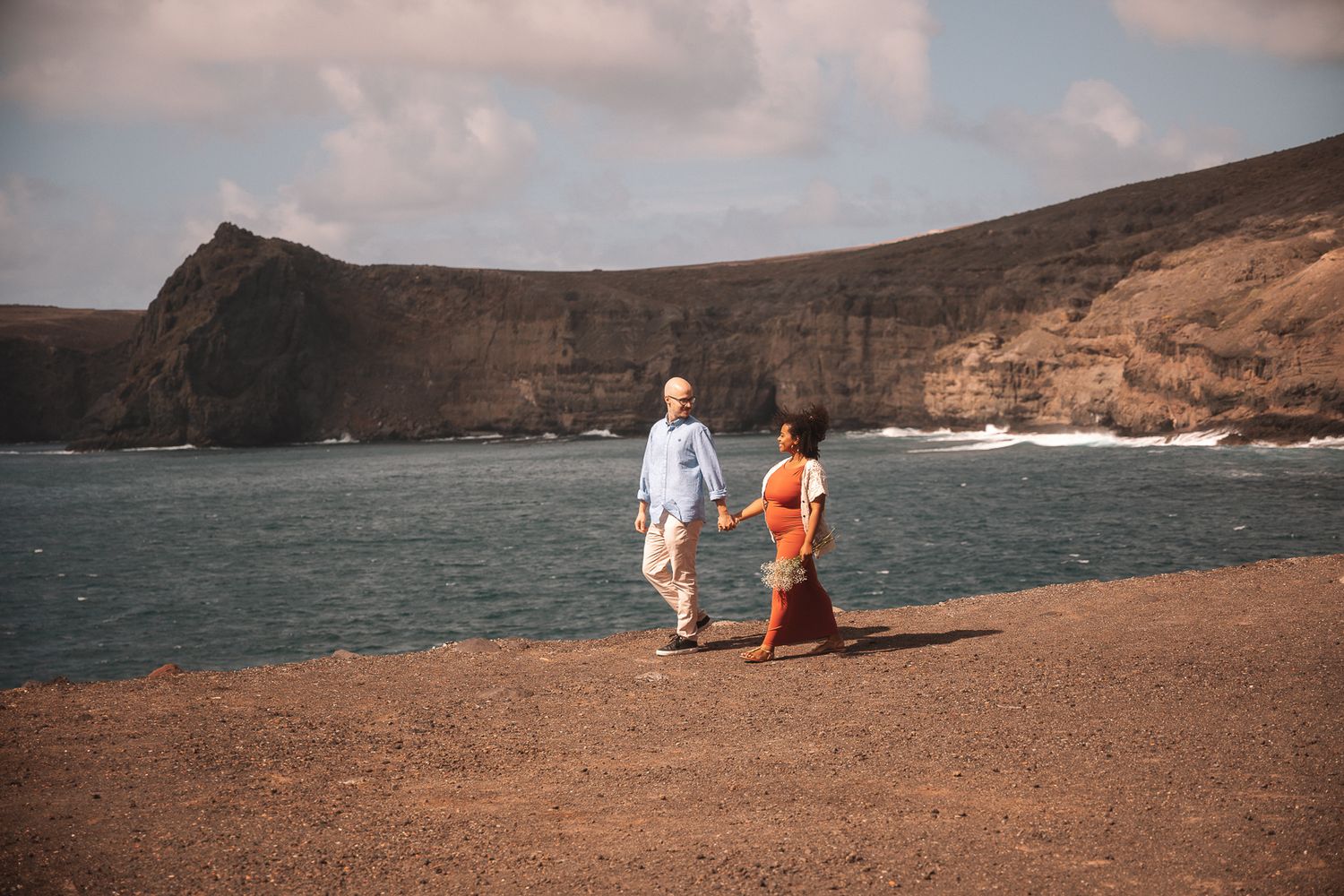 Distant view of people walking along dramatic coastal cliffs and beach landscape.