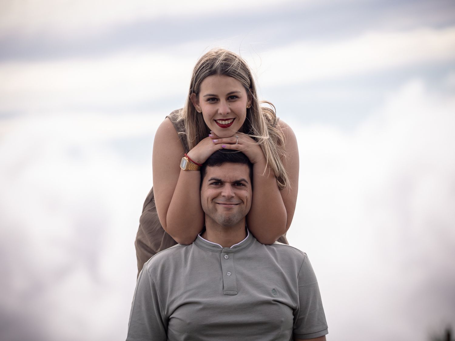 A playful outdoor portrait session with natural lighting and cloudy sky background.