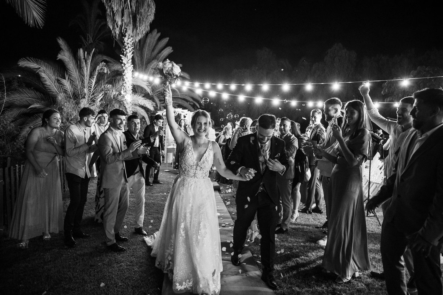 Black and white photo of wedding reception with string lights illuminating the outdoor venue.