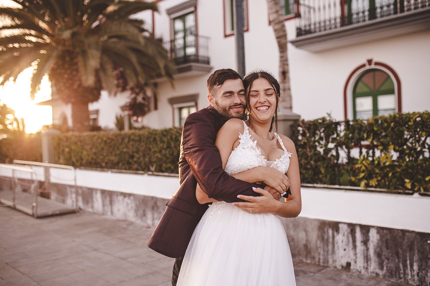 Newlyweds sharing romantic moments during sunset photoshoot near Mediterranean villa.