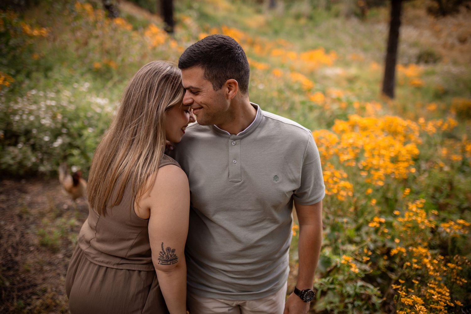 Couple sharing tender moment surrounded by orange wildflowers in natural setting.