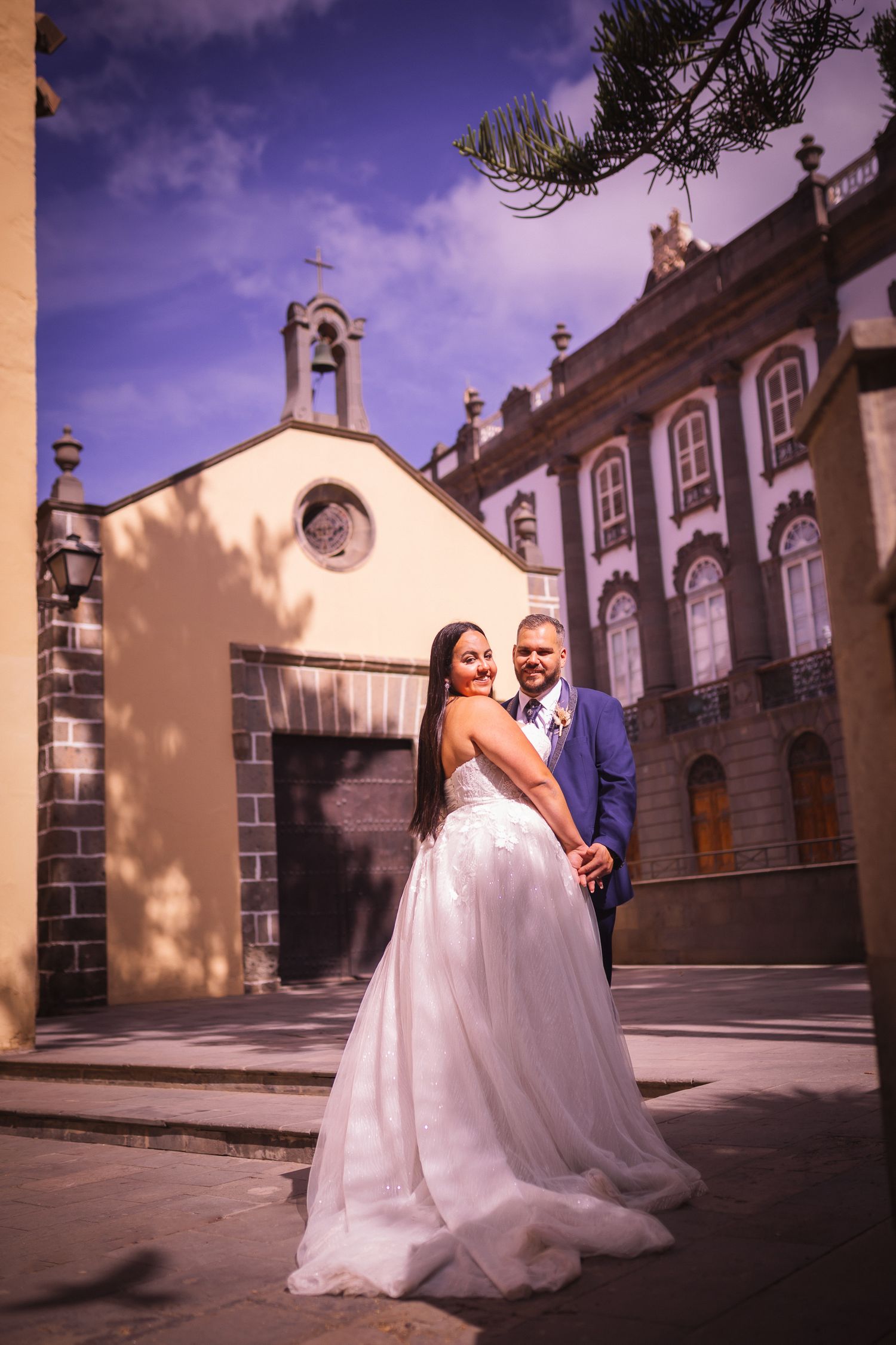 Wedding photography session in front of historic stone building with dramatic lighting.
