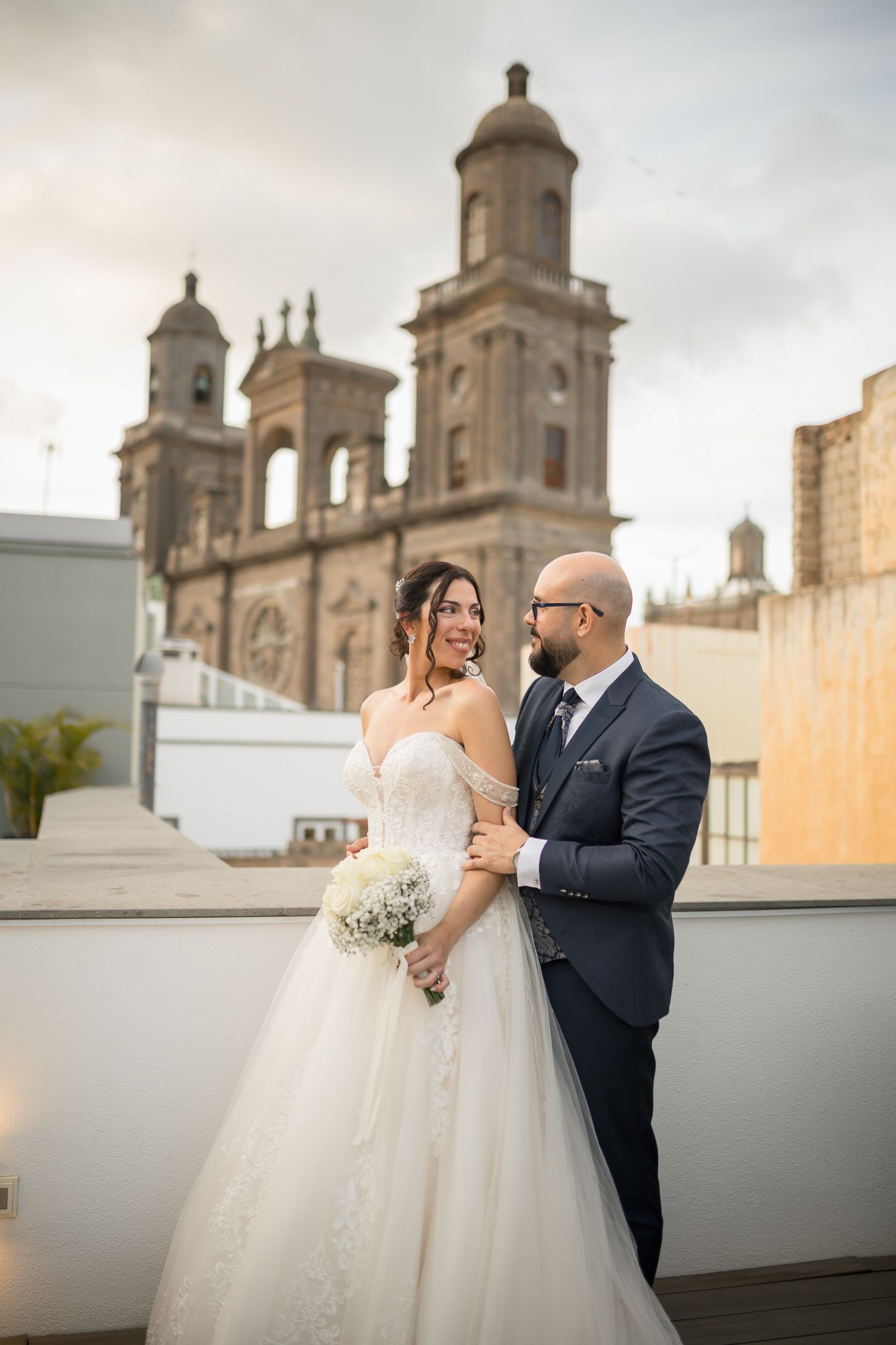 A couple shares an intimate moment during their wedding with a historic cathedral facade in the background.