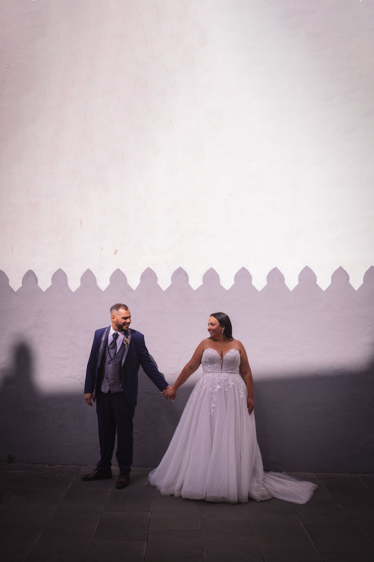 Artistic black and white wedding portraits against minimalist white wall background.