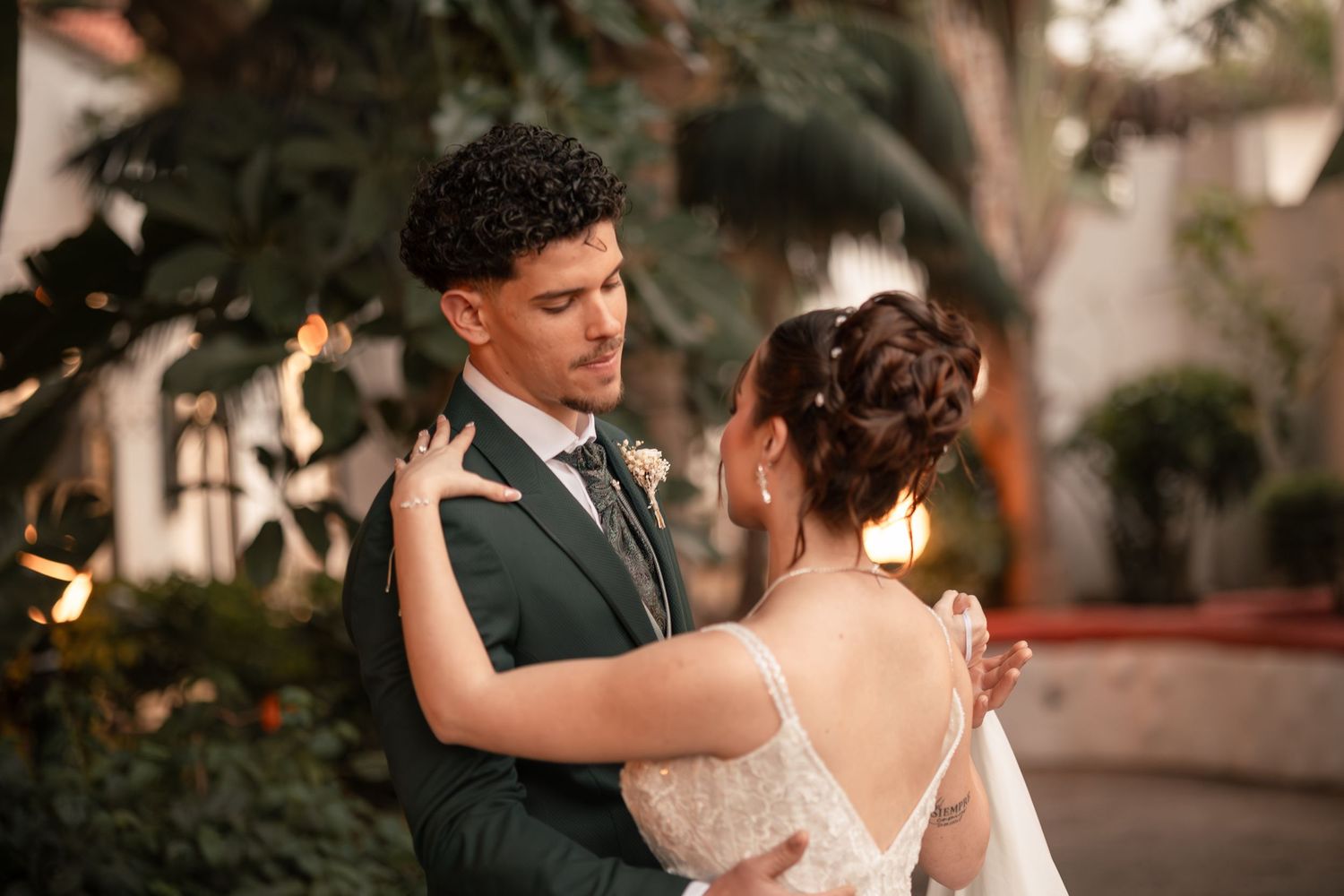 A romantic couple shares an intimate dance at their wedding reception during sunset.