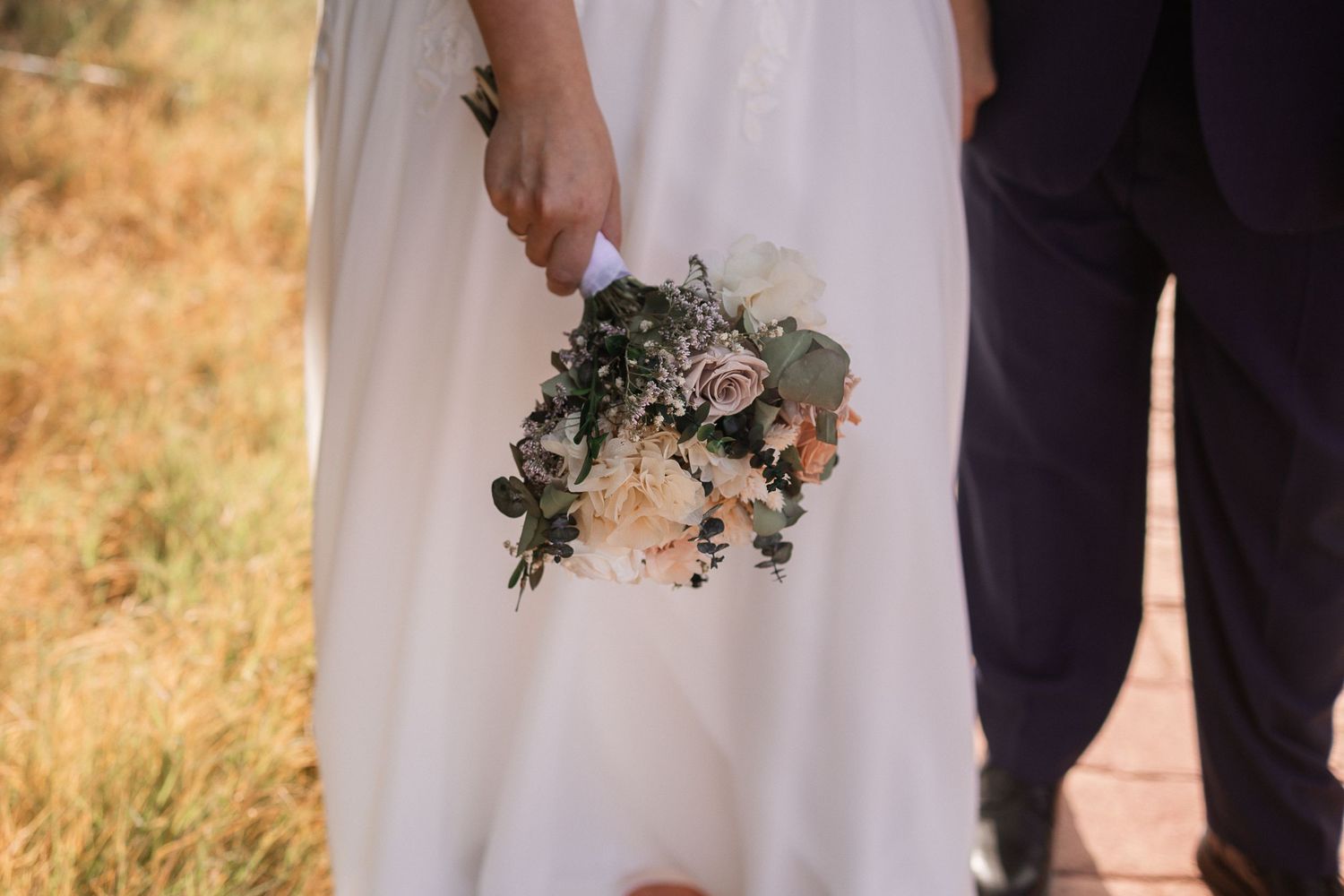 A close-up of a delicate bridal bouquet with greenery and soft flowers.