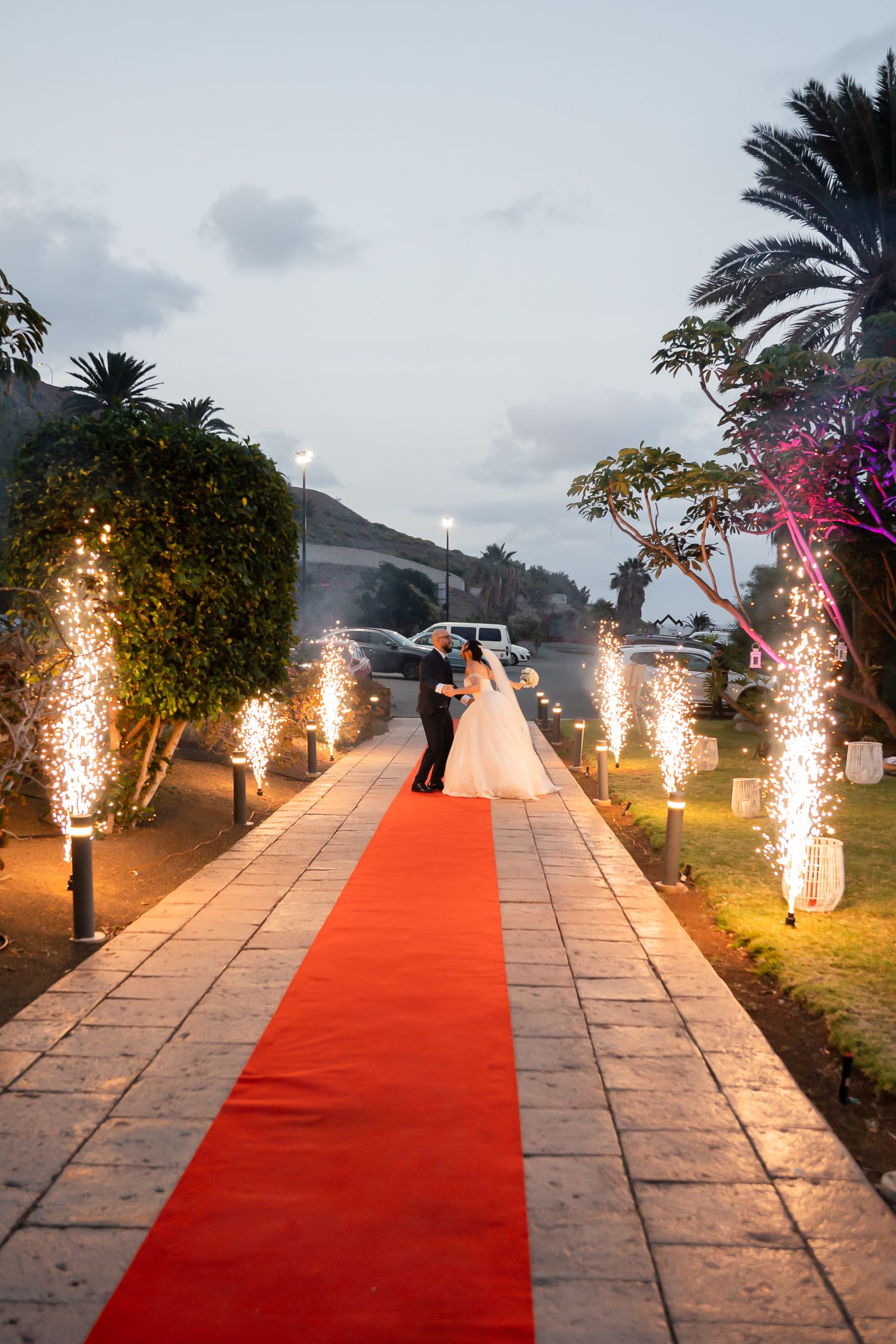 A dramatic red carpet walkway lit with sparklers and pyrotechnics for a wedding exit.