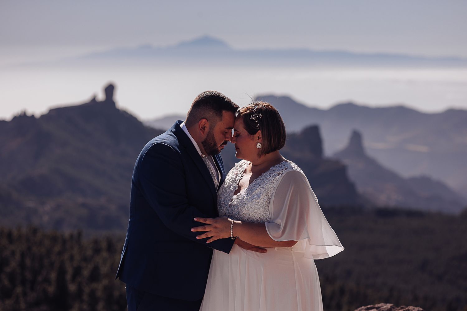 Silhouettes of two people embracing against a backdrop of dramatic mountain landscapes.