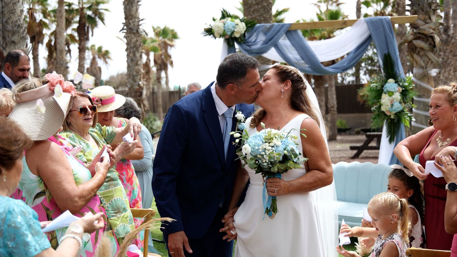 Tropical beach wedding celebration with palm trees and festive decorations.