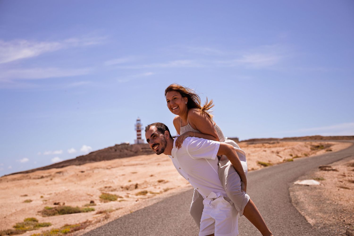 Romantic couple embraces on a scenic desert road during sunset.