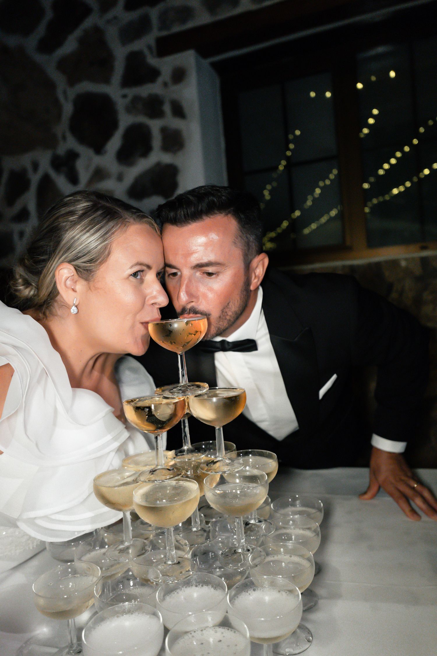 Champagne tower being poured at an elegant wedding reception.