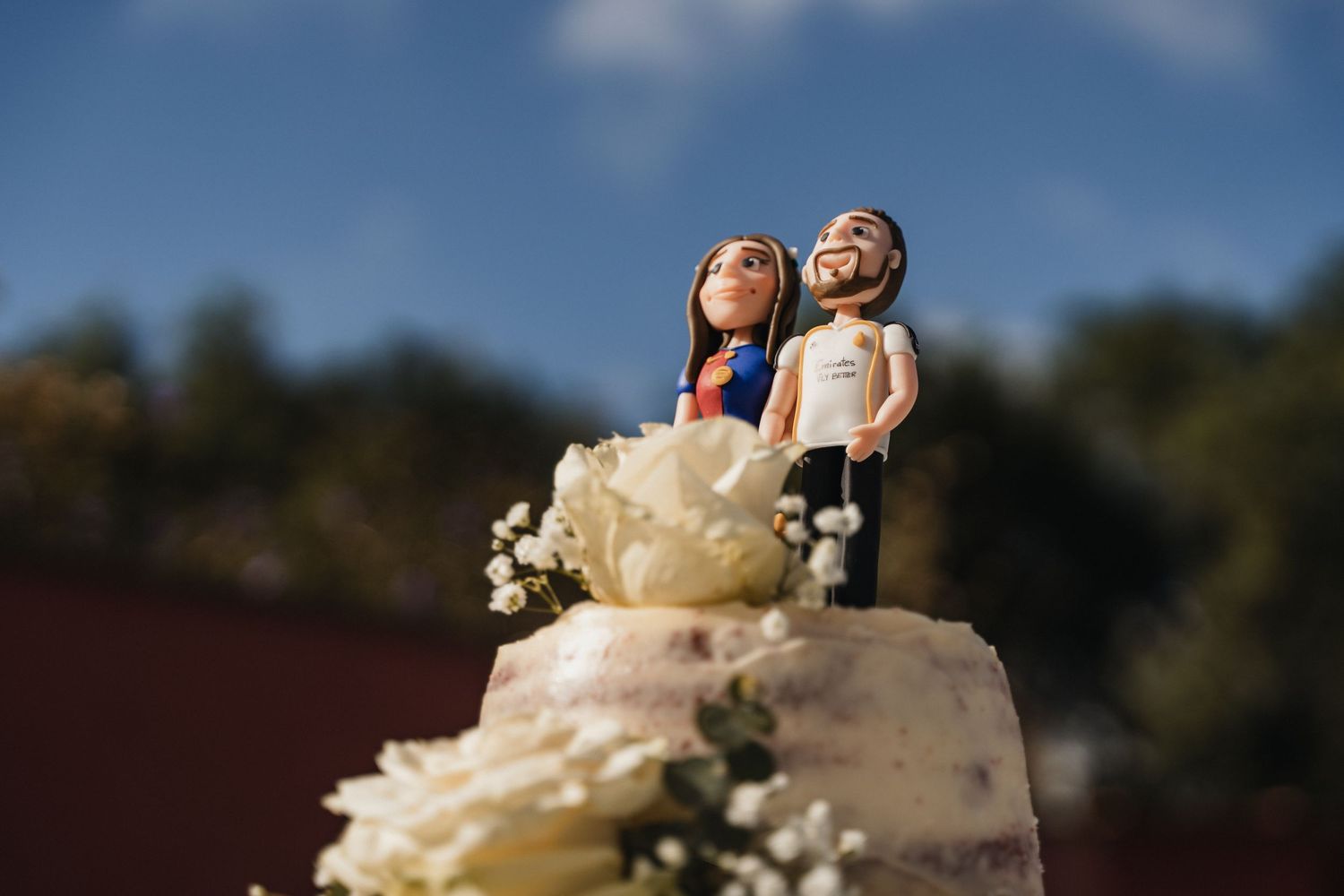 Decorative wedding cake toppers displayed on white frosted tiers with floral accents.