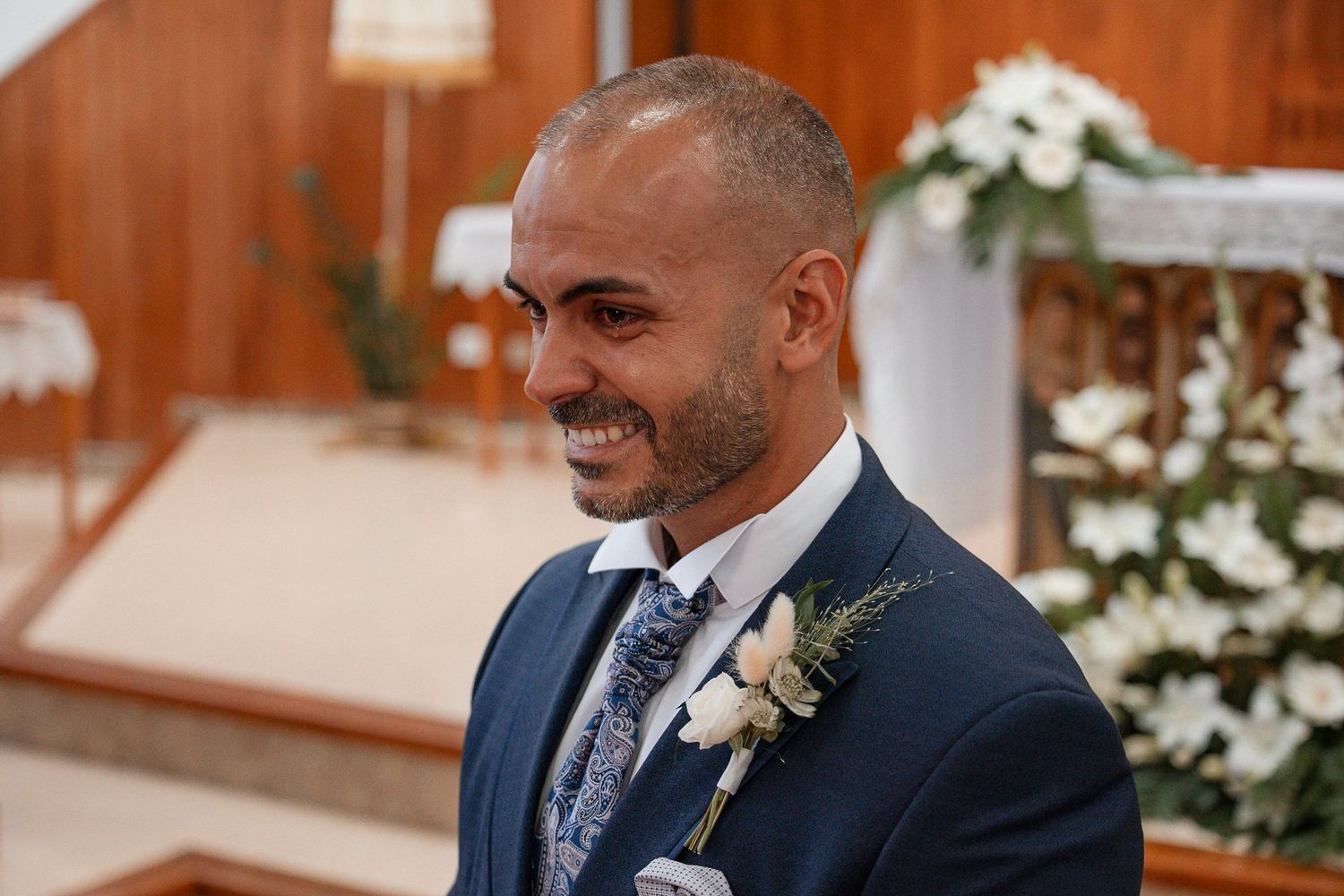Wedding ceremony attendees seated in wooden pews with floral decorations.