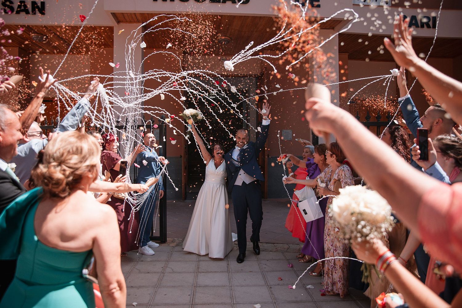 Wedding guests wave sparklers creating a magical tunnel effect as newlyweds exit their ceremony.