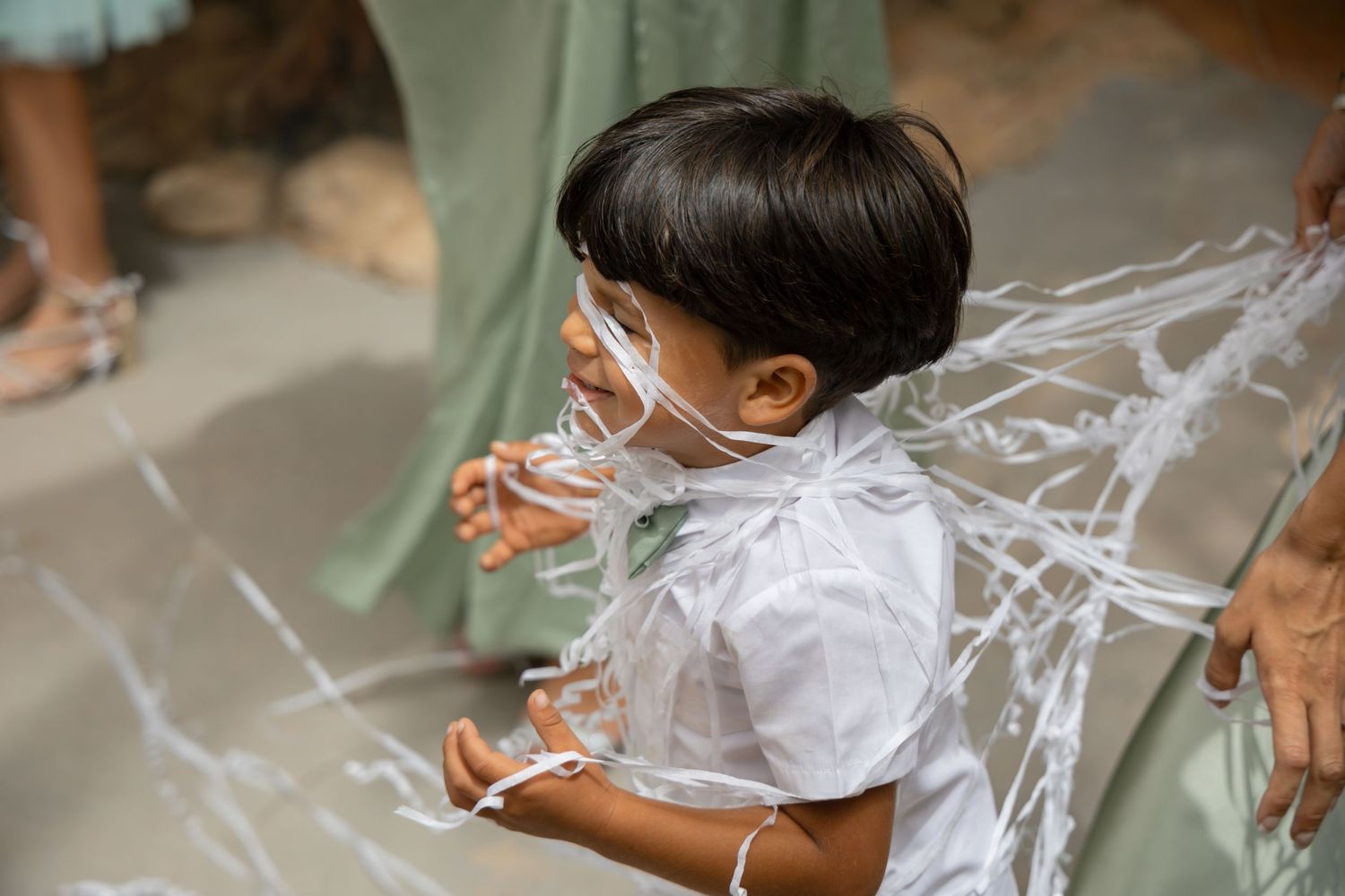 Child plays with flowing white fabric on a light colored floor.