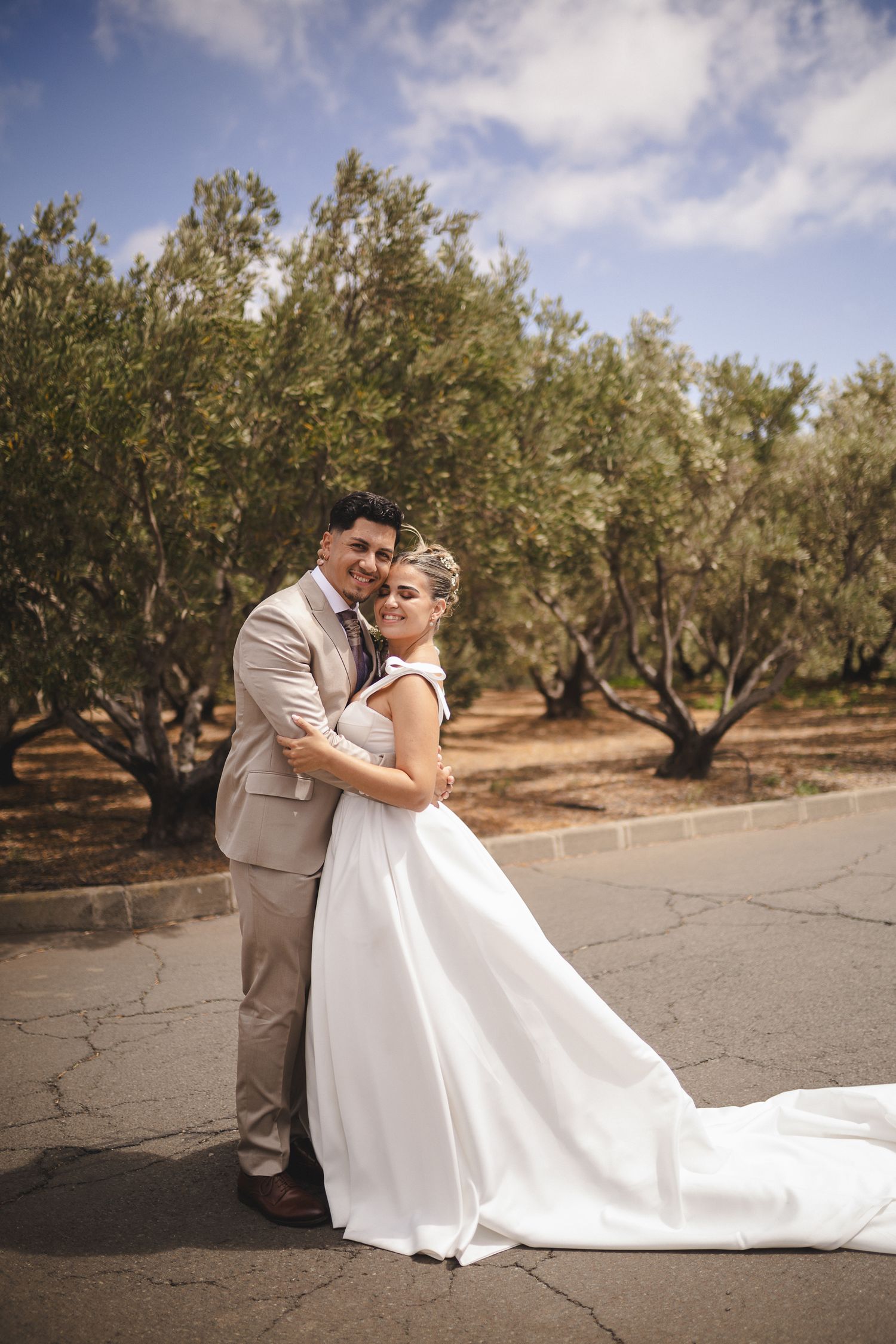 A newlywed couple embraces in an olive grove on their wedding day.