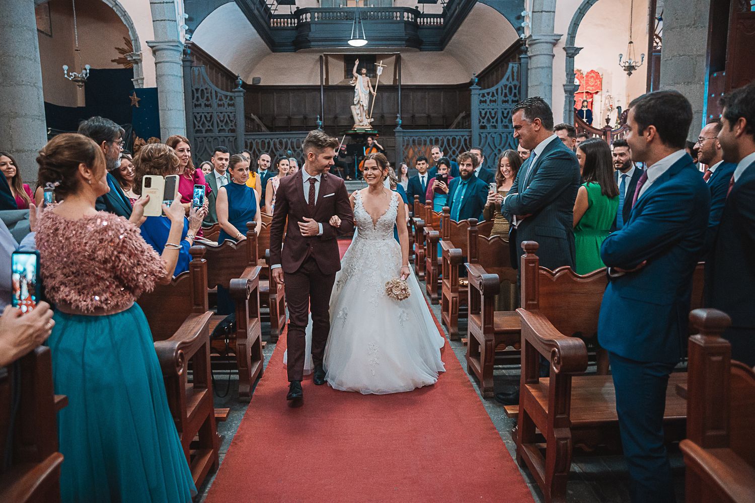 Wedding ceremony in a grand church with teal-dressed wedding party and wooden pews.
